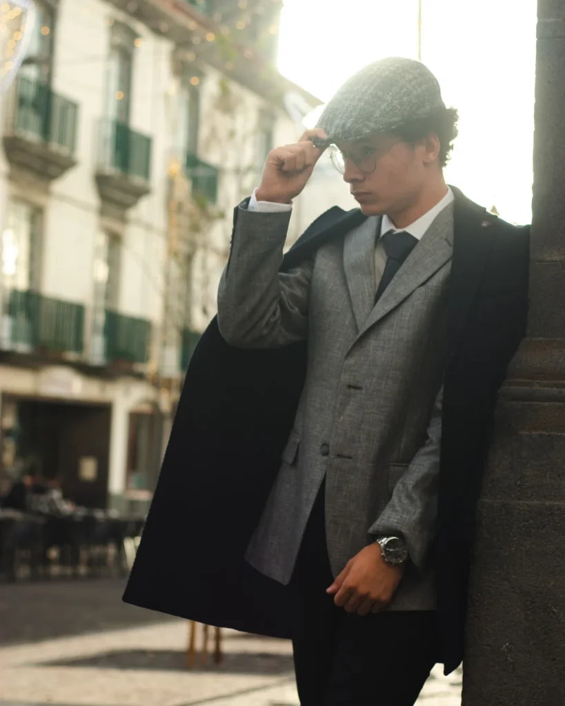 Model in a grey suit and flat cap leaning on a column in Ponta Delgada