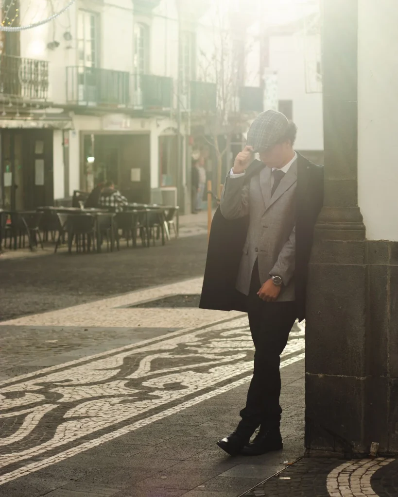 Model in a grey suit and dark overcoat on Portuguese pavement