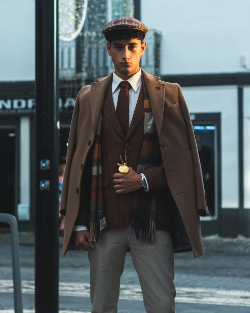 Modelo com sobretudo camel, fato de tweed e relógio de bolso frente à loja Londrina